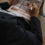 Senior adult solving a crossword puzzle in a newspaper, captured indoors.